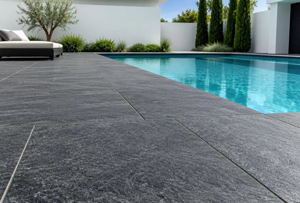 Textured charcoal basalt paving framing a turquoise backyard pool